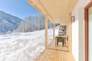 a wooden porch with a table in the snow at Ferienhaus in Klösterle in Klösterle