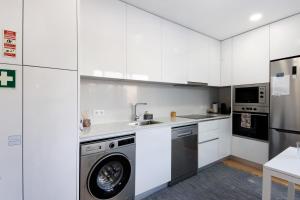 a kitchen with white cabinets and a washer and dryer at Flor de Sá in Aveiro