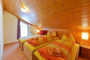 two beds in a room with a wooden wall at Ferienhaus in Klösterle in Klösterle