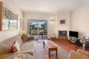 a living room with a couch and a tv at Casa do Ouriço - Cabanas Tavira in Tavira