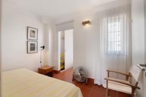 a bedroom with a bed and a window and a fan at Casa do Ouriço - Cabanas Tavira in Tavira