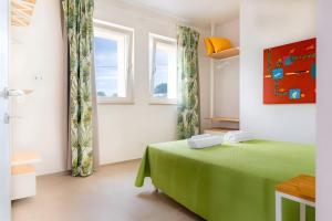 a bedroom with a green bed and two windows at Helianthus in Cisternino