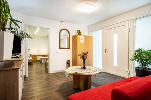 a living room with a red couch and a table with flowers at Nguyen und Le in Neukirch