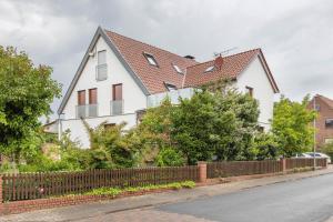 a white house with a fence on a street at Storchenblick in Wunstorf