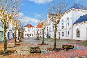 a row of white buildings with trees in a courtyard at Ferienwohnung Itzehoe in Itzehoe