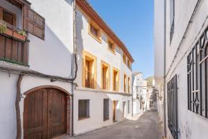 an alley with white buildings and a wooden door at Cueva Del Sereno in Chulilla