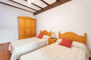 two beds in a bedroom with white walls and wooden ceilings at Cueva Del Sereno in Chulilla