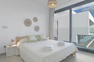 a white bedroom with a bed and a large window at Palacio de pilas 22 in Zahara de los Atunes +20 photos