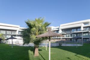 a palm tree and umbrellas in front of a building at Palacio de pilas 22 in Zahara de los Atunes