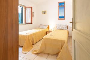 a room with two beds and a window at Appartamenti Le Querce App. Mirto in Capoliveri