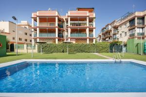 an apartment with a swimming pool in front of a building at Camaleón 7 in Chipiona