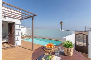 a villa with a pool and a table with a bowl of fruit at Villa Timanfaya in Tías