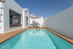 a swimming pool with chairs and a house at Villa Timanfaya in Tías