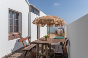 a wooden table with two chairs and an umbrella at Villa Timanfaya in Tías