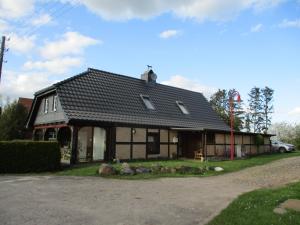 a house with a black roof on a street at Altes Jägerhaus in Lübbenow