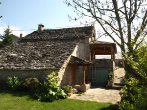 an old stone house with a green garage at L'alouette - Gites Rocheflamme in La Malène
