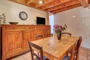 a dining room with a wooden table and a tv at Maison cosy, 5 mins de St Lary in Sailhan