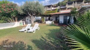 a yard with two white chairs in front of a house at Costa dei Monaci Villas - Tropea in Parghelia