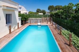 a swimming pool with a wooden deck and a swimming pool at Villa Minetta in Leporano Marina