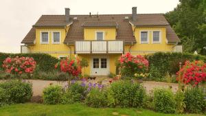 a yellow house with flowers in front of it at Ferienwohnung Fliess in Neuendorf am See