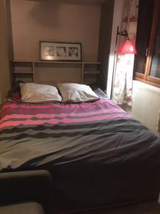 a bed with two pillows and a striped blanket at Studio Fontanarosa centre station in Vars