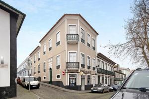 a tall building with cars parked in front of it at Sé Heritage in Angra do Heroísmo