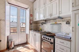 a kitchen with white cabinets and a stove top oven at Estoi Heritage in Estói +29 photos