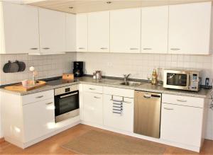 a kitchen with white cabinets and a sink and a microwave at Ferienwohnung Hogh, 55qm, Terrasse in Beuren