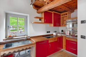 a kitchen with red cabinets and a sink and a window at Dolomites Chalet Pian in Campitello di Fassa