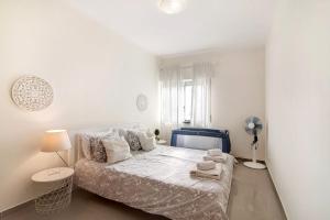 a white bedroom with a bed and a fan at Matinhos House in Faro