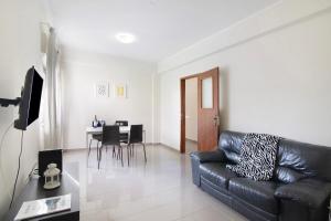 a living room with a black leather couch and a table at Matinhos House in Faro