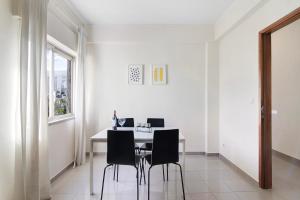 a white dining room with a table and chairs at Matinhos House in Faro