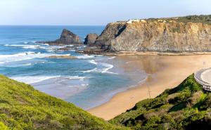 a beach with a road next to the ocean at Casa 5 Flores in Odeceixe
