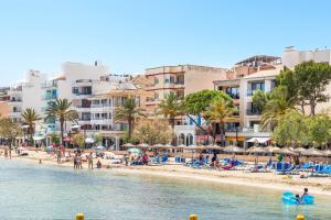 a beach with people and umbrellas and buildings at Voramar in Pollença
