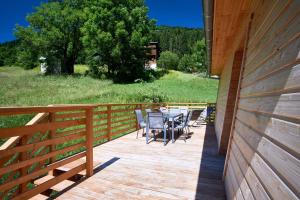 a wooden deck with a table and chairs on it at Chalet le Lys Martagon in Saint-Pierre-dʼEntremont