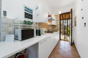a kitchen with white cabinets and a tv on a counter at Kai Mālie Villasimius in Villasimius +19 photos