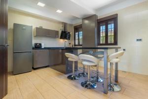 a kitchen with a counter with stools and a refrigerator at Villa Oasis in Lora del Río