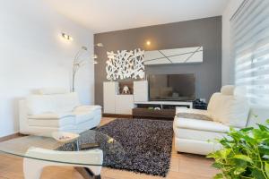 a living room with two white chairs and a television at Villa Oasis in Lora del Río