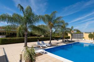 a swimming pool with palm trees and lounge chairs at Villa Oasis in Lora del Río
