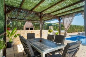 a patio with a wooden pergola and a table and chairs at Villa Oasis in Lora del Río