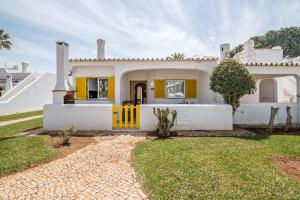 a large white house with a yellow door at Casa O12 in Vilamoura