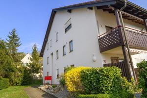 a white building with a balcony and some bushes at Ferienwohnung Wagner mit 35 qm Fr in Bad Bellingen