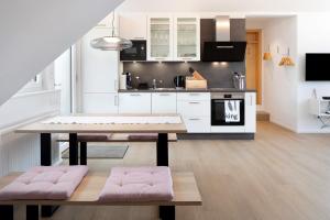 a kitchen with white cabinets and a table with pink seats at Ferienwohnung Hörnleberg in Gutach im Breisgau