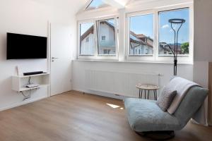 a living room with a chair and a tv and windows at Ferienwohnung Hörnleberg in Gutach im Breisgau