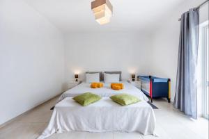 a white bedroom with two beds with orange pillows at Casa Cláudia - Centro Histórico in Lagos