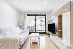a living room with a white couch and a tv at Valencia Playa in Valencia +20 photos