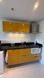 a kitchen with yellow cabinets and a microwave at Granja Brasil , Studio Itaipava in Araras Petropolis