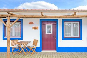 a house with a red door and two chairs at Herdade Vale de Gaios in Odemira