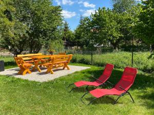 a picnic table and two red chairs in the grass at Ferienhaus Sweethome - mit Garten in Bad Sachsa