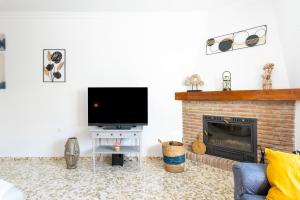 a living room with a fireplace and a flat screen tv at Villa Cañete in Benamocarra